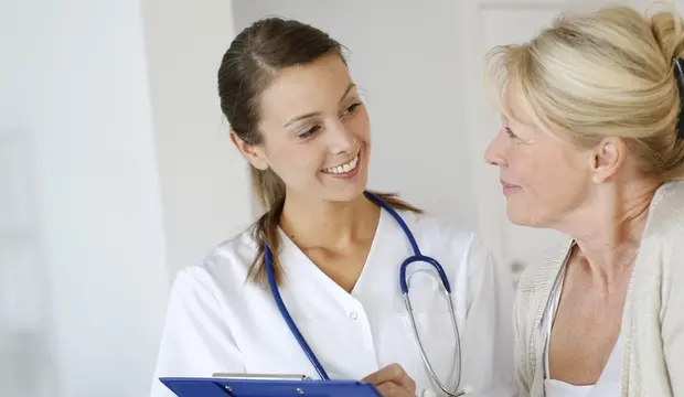 Une infirmière discute en souriant avec une résidente